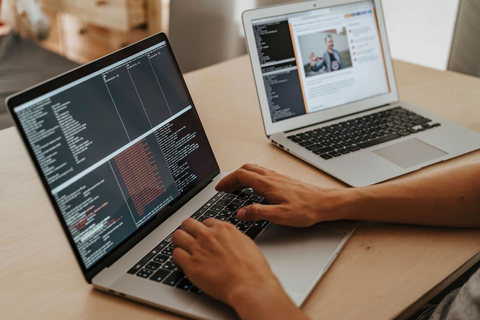 Laptop mit Code im Terminal, daneben ein zweiter Laptop mit einem Videocall