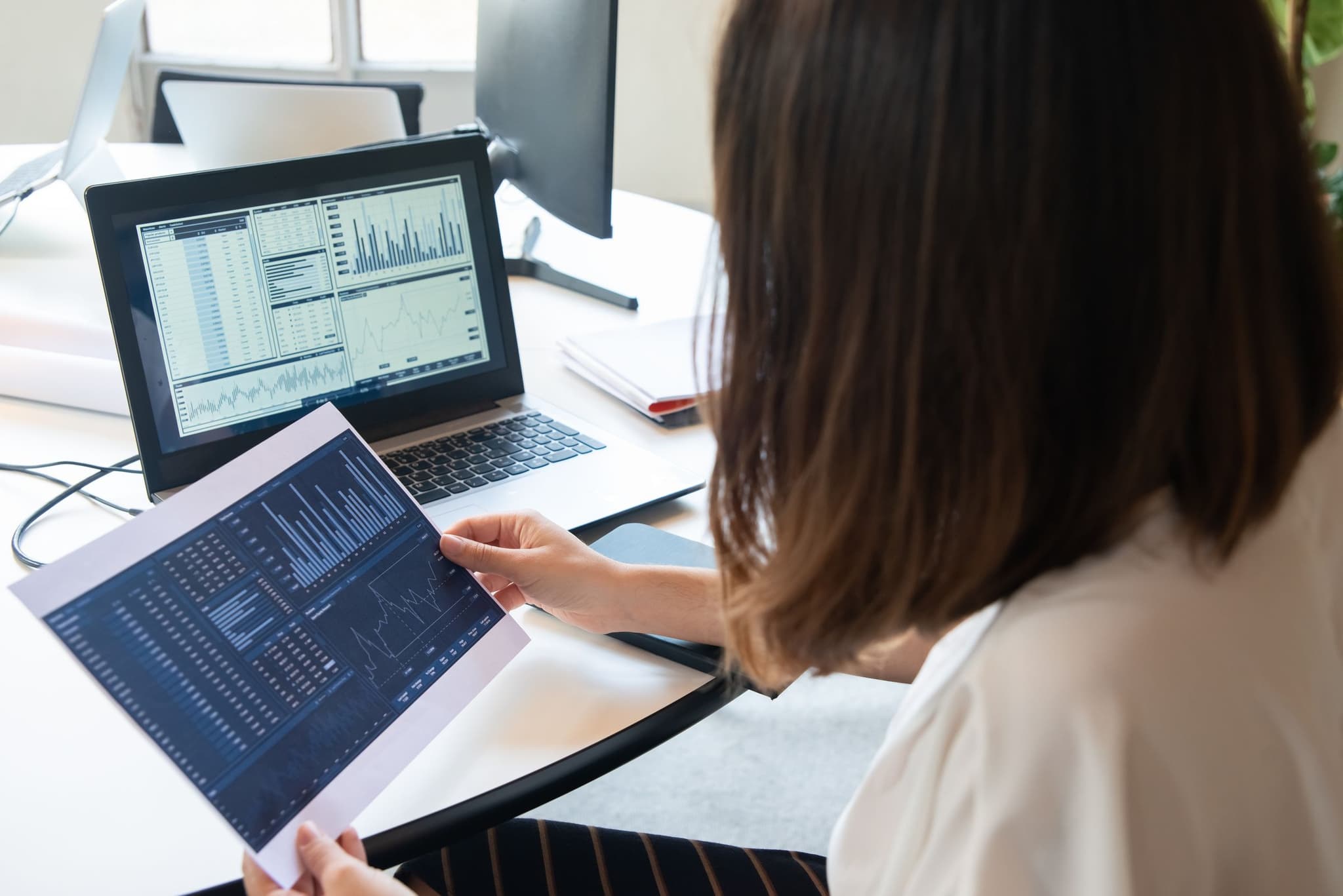 Person reviewing revenue figures on a tablet and laptop